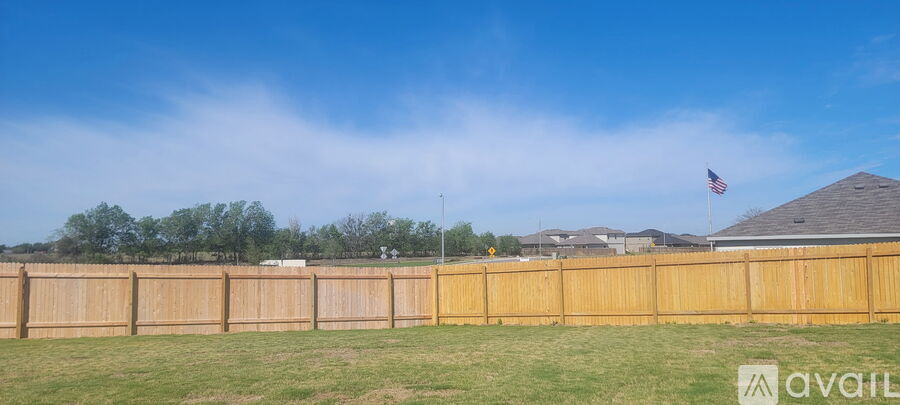 A wooden fence with a flag on top and a house in the background.