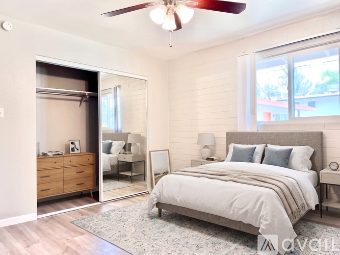 A bedroom with a large bed, a dresser, a mirror, and a ceiling fan.