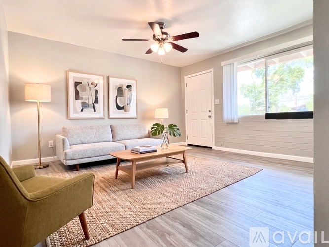 A living room with a white couch, a green armchair, a wooden coffee table, and two framed pictures on the wall.