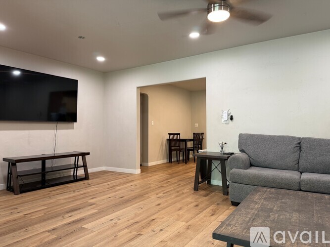 A living room with a grey couch, a wooden floor, and a television.