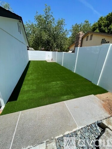A white fence encloses a small grassy area.