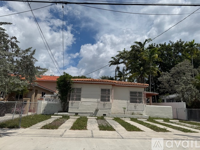 A house with a red roof and a fence in front of it.