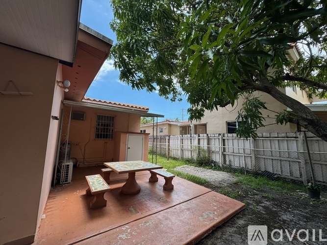A patio with a table and chairs is surrounded by a fence and trees.