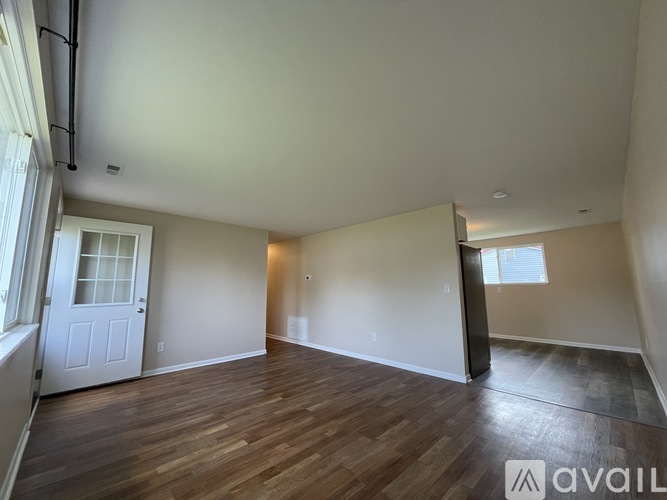 A spacious room with wooden flooring and white walls.
