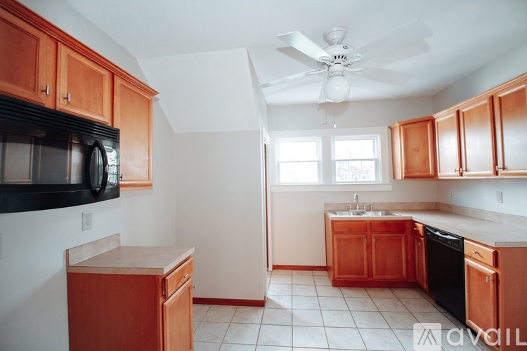 A kitchen with wooden cabinets and a black microwave.