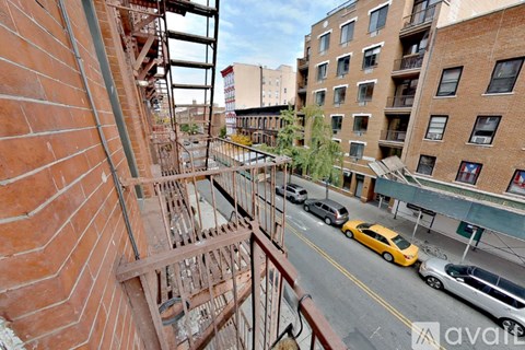 A view from a balcony overlooking a street with cars and buildings.