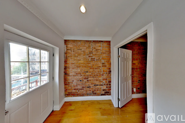 A room with a brick wall and wooden floors.