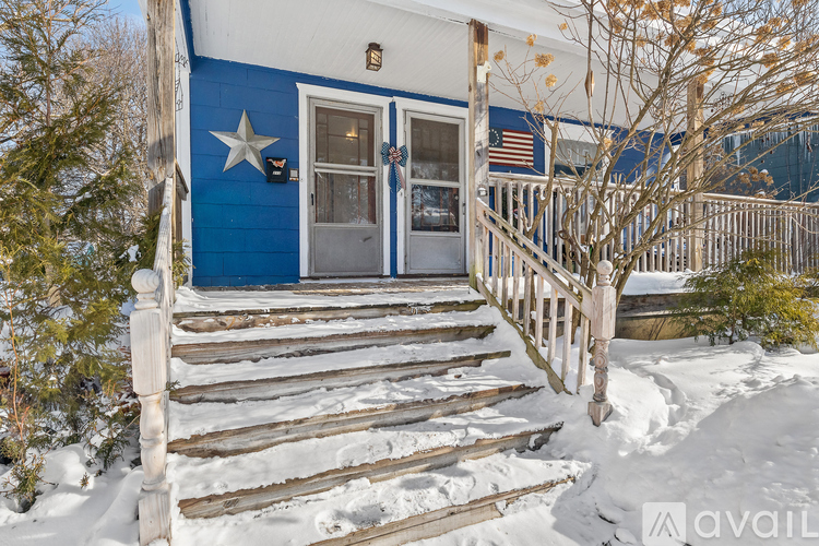 A blue house with a wooden staircase leading to the door.