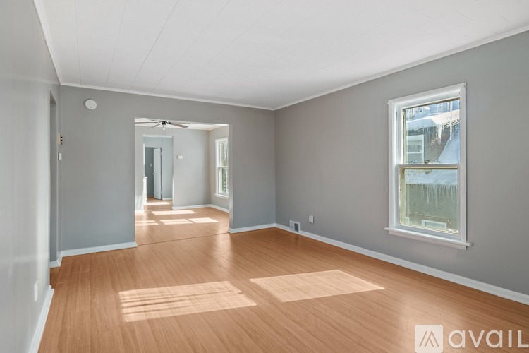 A spacious room with wooden floors and a large window.