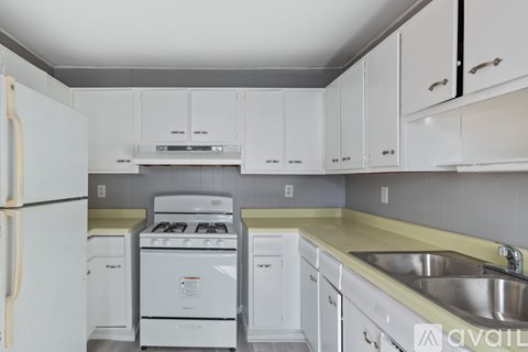 A kitchen with white cabinets and a white fridge.