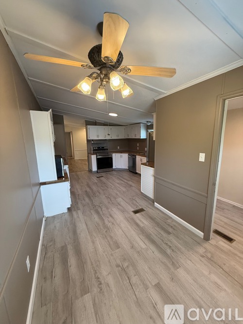 A room with a ceiling fan and wooden flooring.