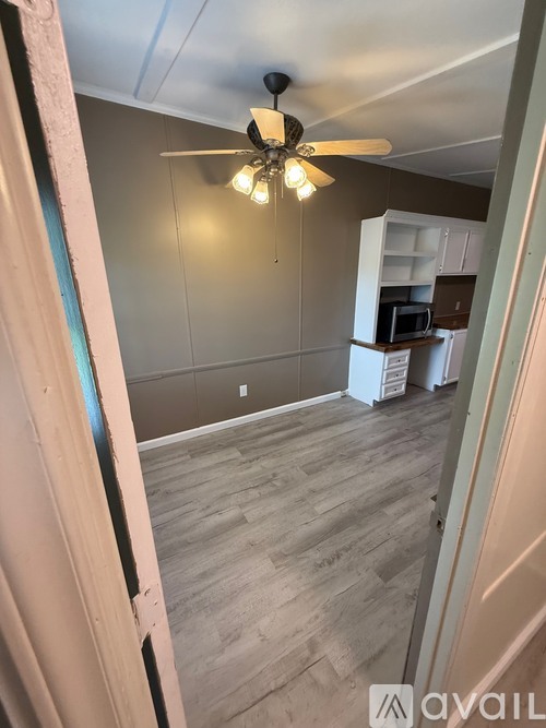 A room with a ceiling fan and wooden flooring.