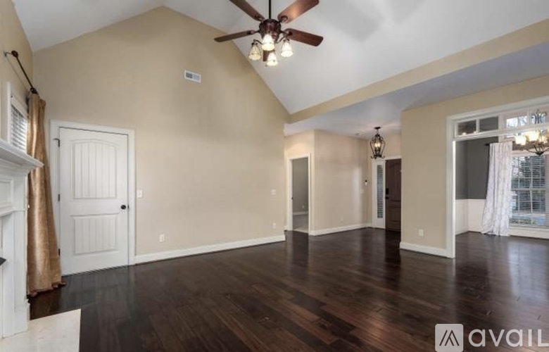 A spacious room with a ceiling fan and hardwood floors.