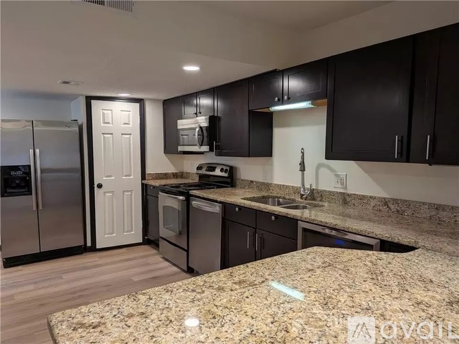 A kitchen with black cabinets and granite countertops.