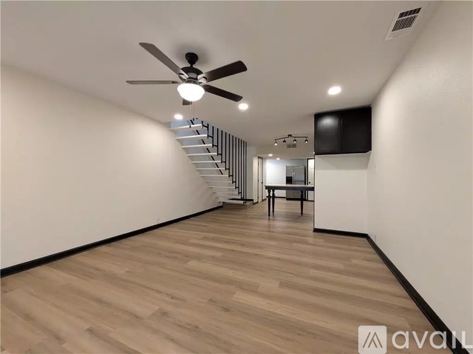 A spacious room with wooden flooring and a ceiling fan.