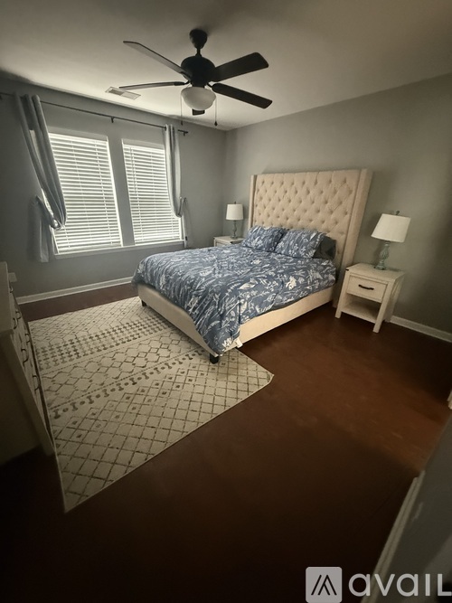 A bedroom with a bed, nightstand, and fan.