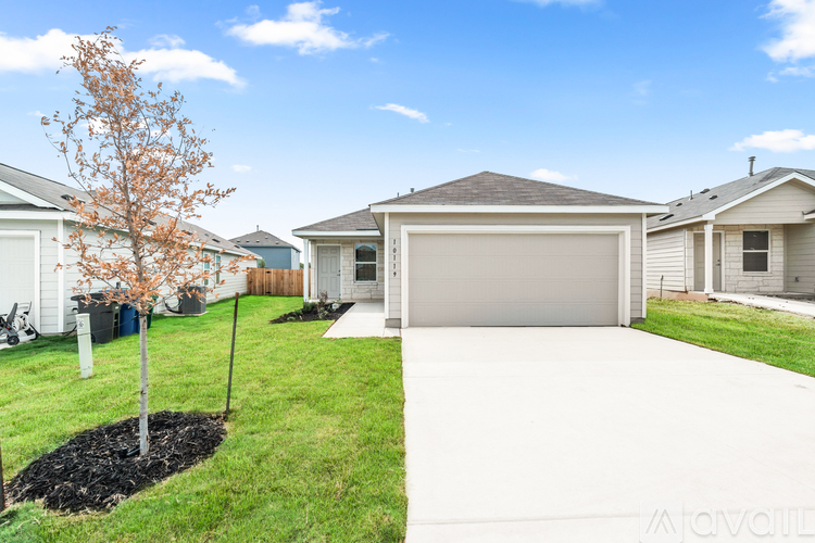 A house with a white garage door and a tree in the front yard.