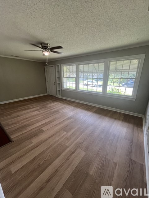 A room with a ceiling fan and wooden flooring.