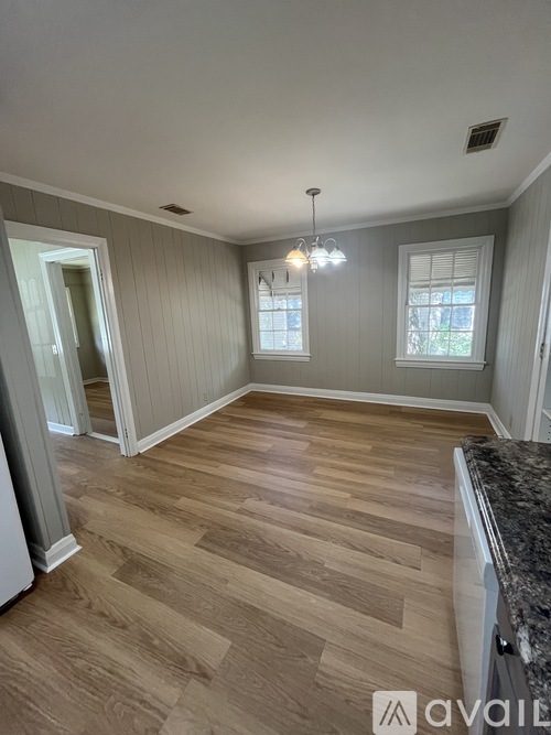 A room with wooden flooring and a chandelier.
