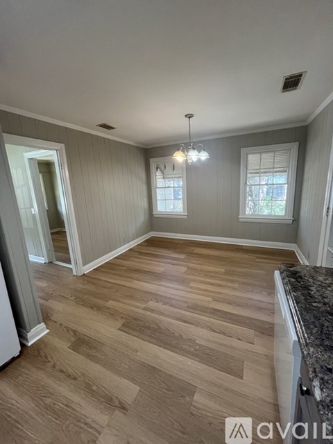A room with wooden flooring and a chandelier.
