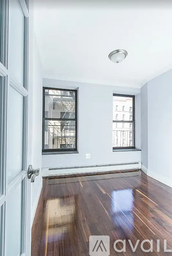 A room with a wooden floor and a window with a view of a balcony.