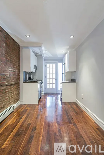 A room with wooden floors and a brick wall.