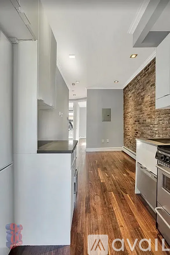 A kitchen with white cabinets and a wooden floor.