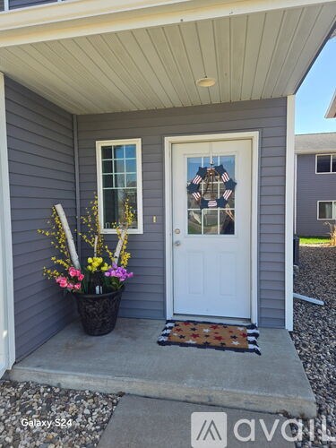 A front porch with a white door and a planter with flowers.