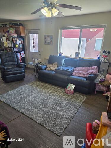 A living room with a black leather couch and a ceiling fan.