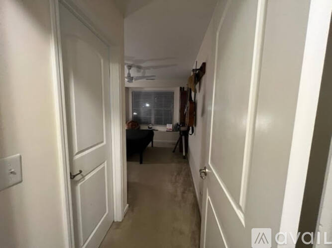 A narrow hallway with a white door on the left and a white door on the right.