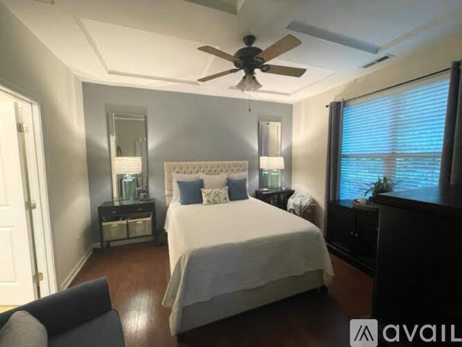 A bedroom with a bed, a chair, and a ceiling fan.