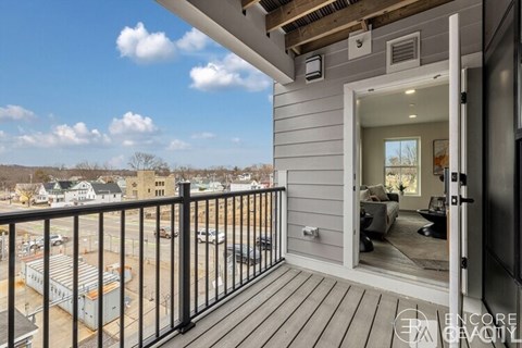 A balcony with a view of a parking lot and buildings.
