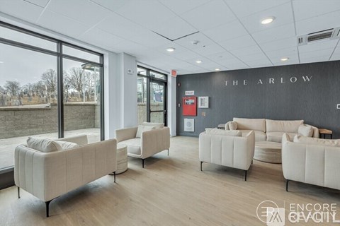 A living room with white furniture and a black wall with the word "The Arlow" on it.