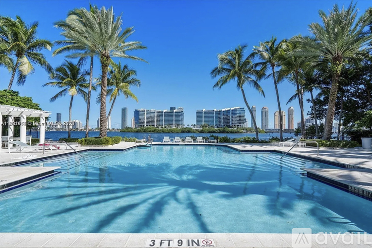 A pool with palm trees and buildings in the background.