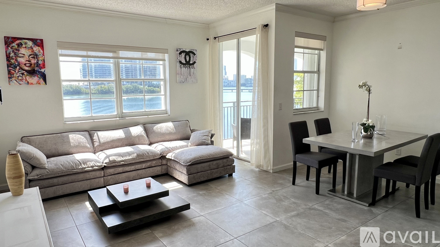 A living room with a grey sofa, a black coffee table, and a dining table with chairs.