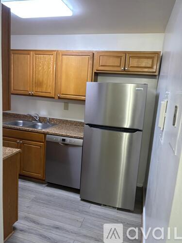 A kitchen with a stainless steel refrigerator and wooden cabinets.