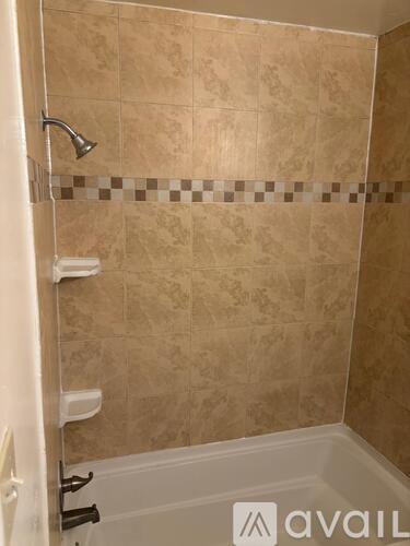 A bathroom with beige tiles and a white bathtub.