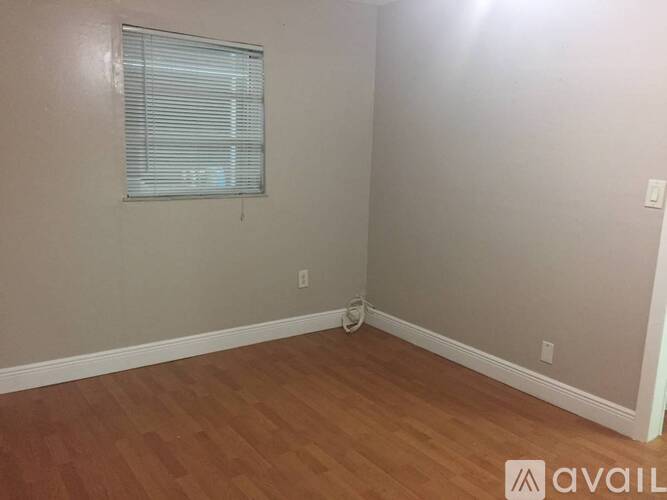 A room with wooden flooring and a window with blinds.