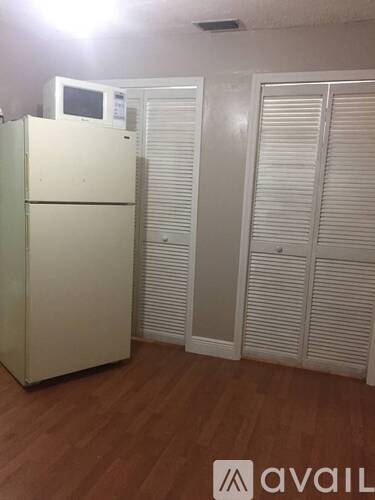 A white fridge with a digital display on top is in a room with wooden flooring and white closet doors.