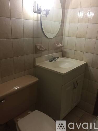 A bathroom with a toilet, sink, and mirror.