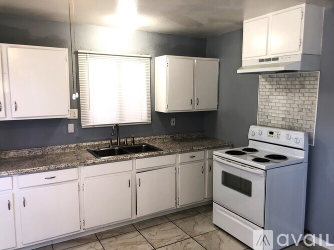 A kitchen with white cabinets and a white stove top oven.