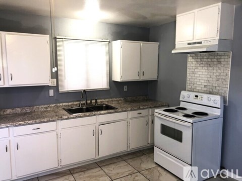 A kitchen with white cabinets and a white stove top oven.