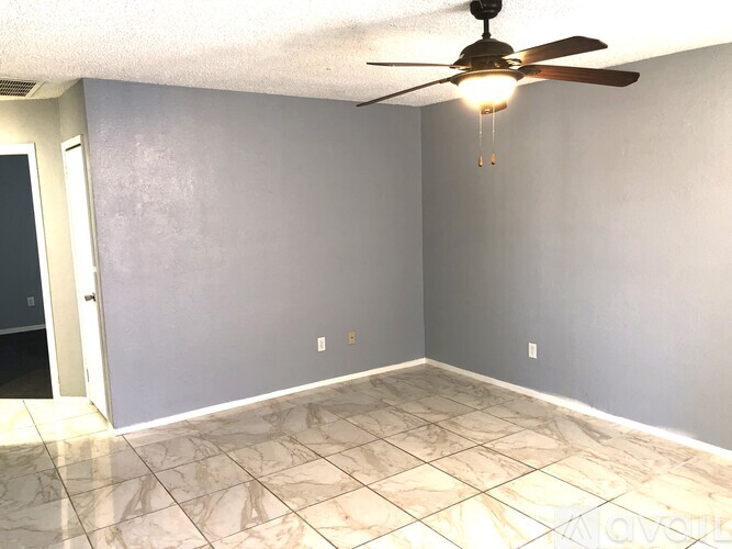 A room with a ceiling fan and tile flooring.