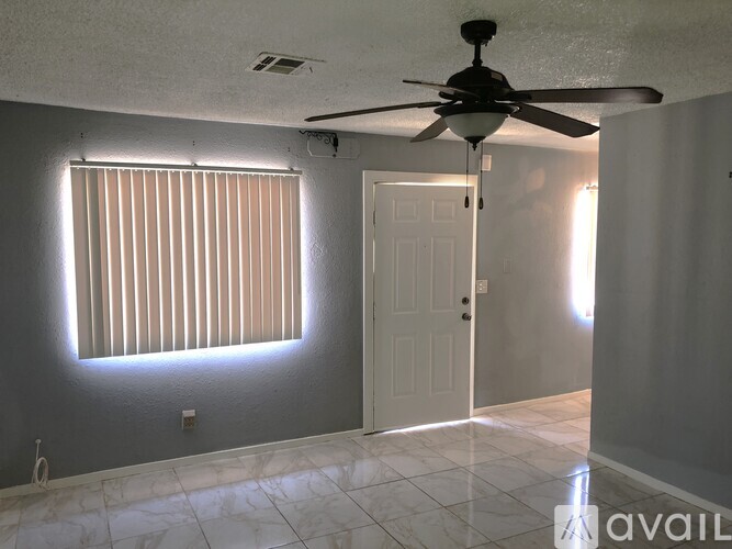 A room with a ceiling fan and a window with blinds.