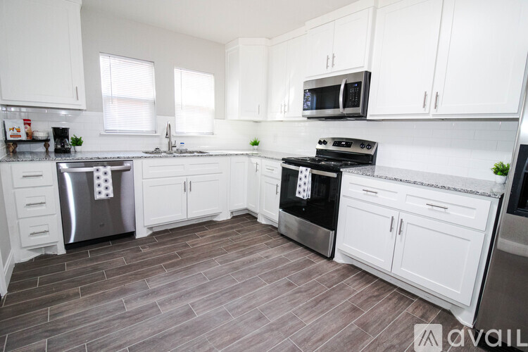 A kitchen with white cabinets and a wooden floor.