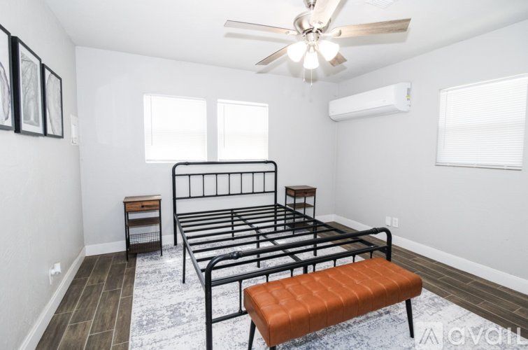 A bedroom with a bed, bench, and a ceiling fan.