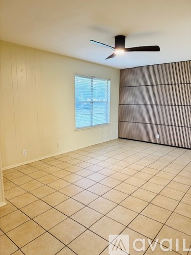 A room with a ceiling fan and a window with blinds.