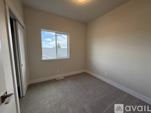 A room with a window showing a view of the sky and clouds.
