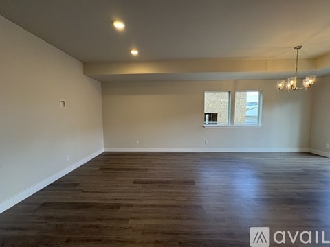 A spacious room with wooden flooring and a window with a view of a building outside.