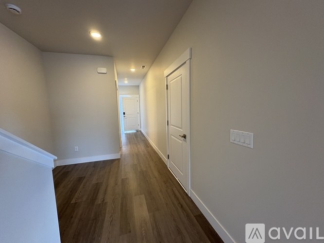 A long hallway with wood floors and white walls.